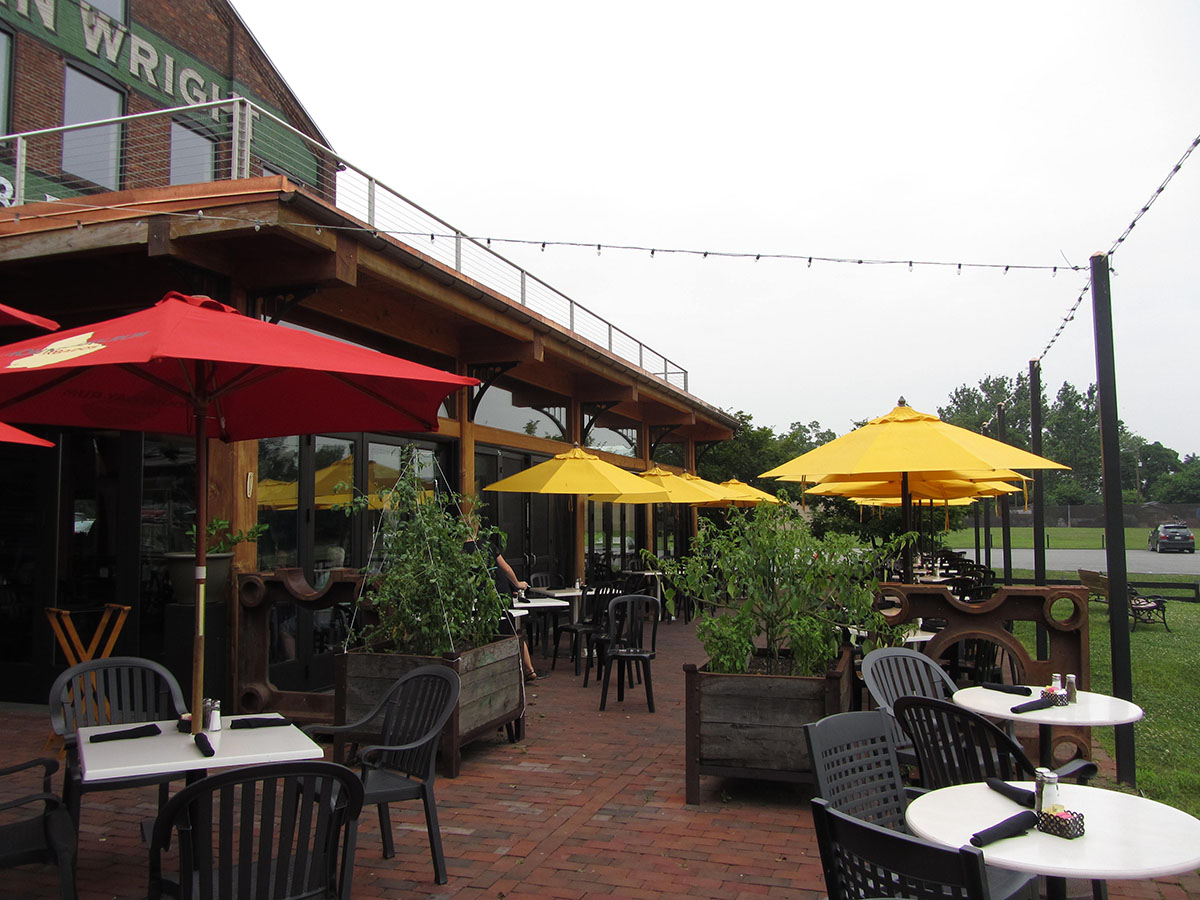 yellow and red umbrellas with lights reaching across above a brick patio with tables