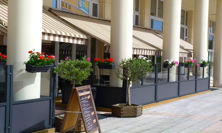 tan and white pin striped awning with restaurant sign in front and flowers