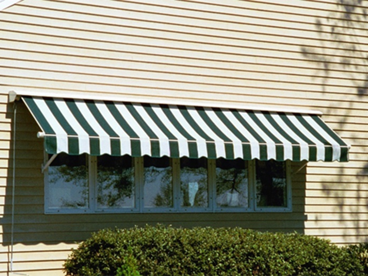 close up of siding with green and white striped awning over a narrow set of windows