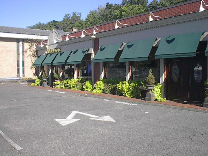 7 green awnings over windows and doors of a storefront