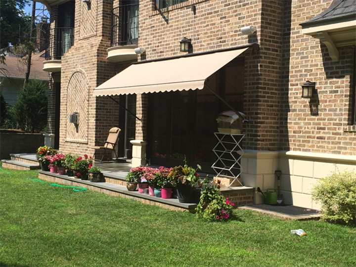 Cream colored awning over entrance with small garden on steps