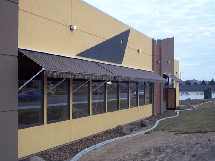 side of store with brown awnings over windows