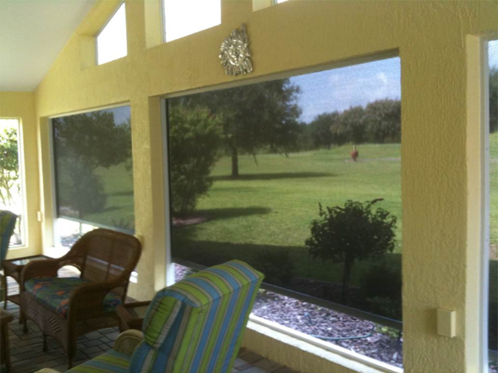 inside a yellow sunroom looking out at the yard through large screens