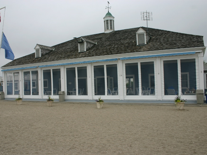 restaurant on a beach with sand surround the building and a blue flag hanging