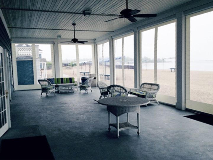 enclosed sun room with gray flooring and ceiling fans with a couple pieces of furniture