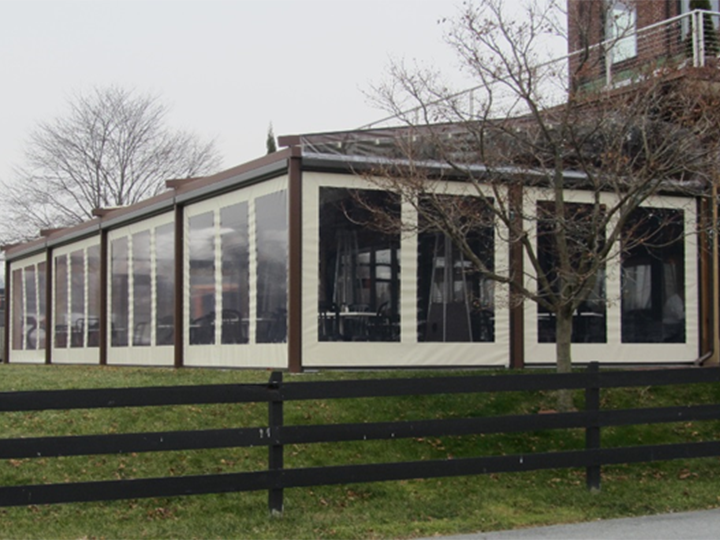 pergola with roll down shades and grassy area with a black fence